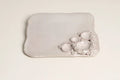 A light gray ceramic dish with a rounded rectangular shape, featuring a textured, organic cluster of small raised bowls on one side, set against a plain off-white background.