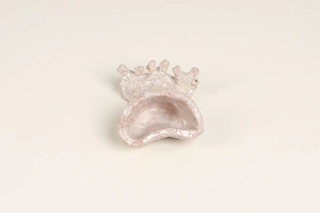 A small decorative shell-shaped dish or holder with a textured, glittery finish, shown on a plain off-white background.